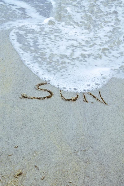 Λέξη στην άμμο με κύμα στον ωκεανό — Φωτογραφία Αρχείου