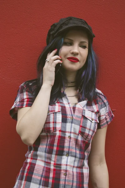 Hipster woman with mobile phone on red wall — Stock Photo, Image