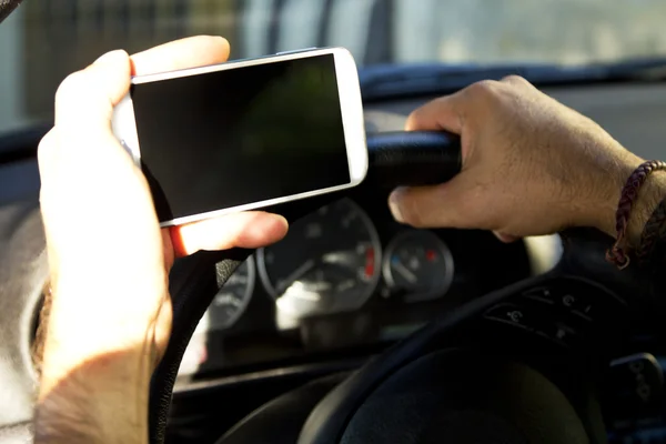 Hombre sentado en el coche con el teléfono móvil en la mano — Foto de Stock