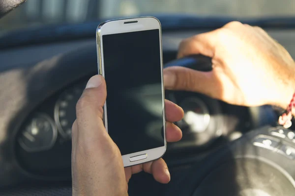 Hombre sentado en el coche con el teléfono móvil en la mano — Foto de Stock