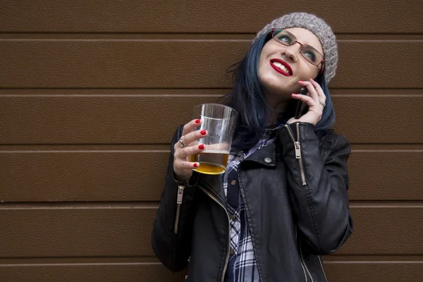 Hipster chica bebiendo una cerveza con el teléfono móvil — Foto de Stock