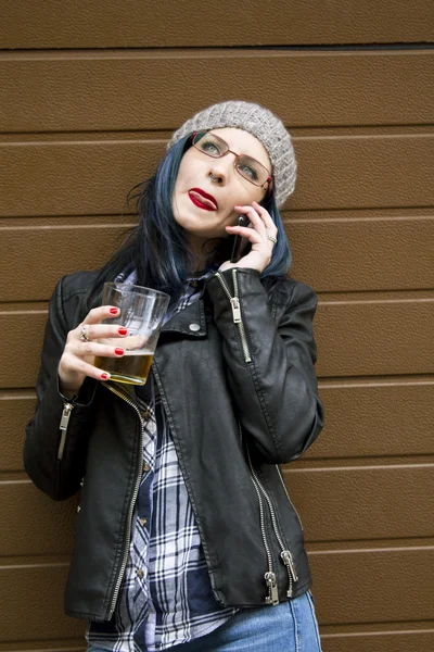 Jeune femme buvant de la bière avec téléphone portable — Photo