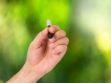 Yeşil arka planda kalemi olan el