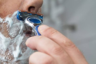 Adam banyoda sakalını kesiyor.