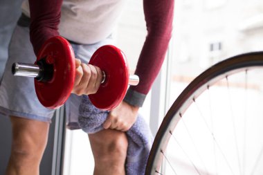 Adam spor salonunda dambıl yapıyor.