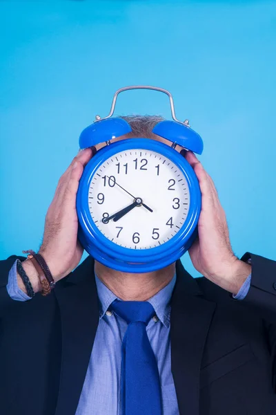 businessman holding alarm clock on his face