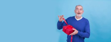 Mutlu tatiller, cemaatim! Çekici sıradan bir adamın portresi mavi arka planda izole edilmiş hediye kutusunu veriyor.