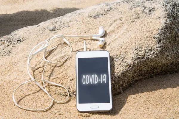 Mobile Phone Headphones Covid Text Sand Beach — Stok fotoğraf