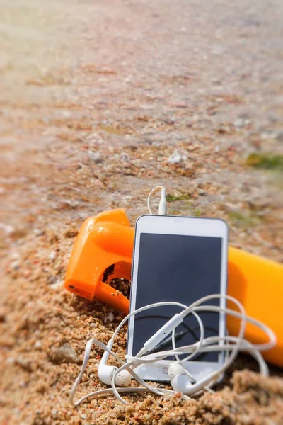 Teléfono Móvil Con Auriculares Loción Bronceadora Arena Playa —  Fotos de Stock