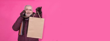 Alışveriş zamanı. Alışveriş çantalı modern son sınıf öğrencisi bir telefon görüşmesi yapıyor. Tüketim, alışveriş, yaşam tarzı konsepti