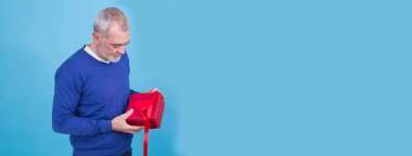 Mutlu tatiller, cemaatim! Çekici sıradan bir adamın portresi mavi arka planda izole edilmiş hediye kutusunu veriyor.