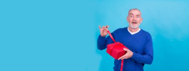 Mutlu tatiller, cemaatim! Çekici sıradan bir adamın portresi mavi arka planda izole edilmiş hediye kutusunu veriyor.