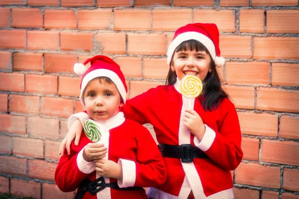 Szczęśliwe Zabawne Dzieci Kostiumie Świętego Mikołaja Jedzące Spiralne Lizaki — Zdjęcie stockowe
