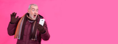 Şaşırmış yüz ifadesi olan bir adam cep telefonu kullanıyor.