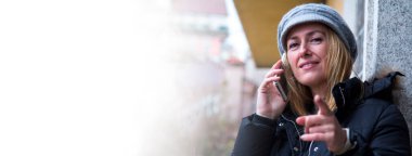 Akıllı telefon kullanan ve parmakla işaret eden gülümseyen kadın.