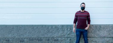 Yüzünde tıbbi maske olan genç bir adam kendini virüslerden ve enfeksiyonlardan koruyor. 