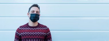 Yüzünde tıbbi maske olan genç bir adam kendini virüslerden ve enfeksiyonlardan koruyor. 