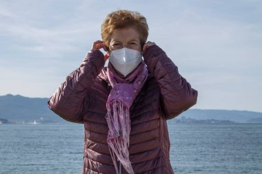 Tek kullanımlık tıbbi maskeli yaşlı bir kadının portresi. Coronavirüs salgını sırasında kamusal alanlarda güvenlik.