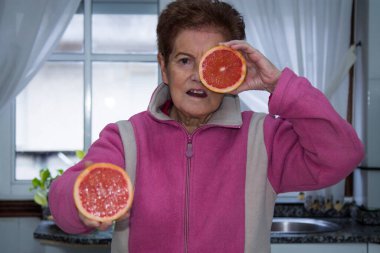 Yüzüne greyfurt, diyet ve sağlık konsepti tutan yaşlı bir kadın.