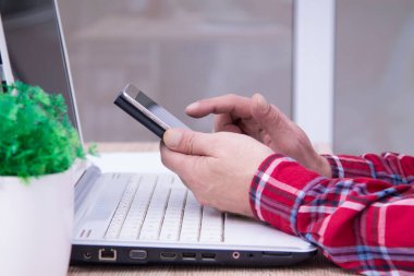 Bilgisayarlı ve cep telefonu kullanan bir adam.