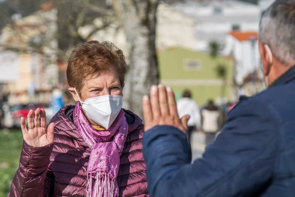senior people with masks greeting each other on the street in times of pandemic