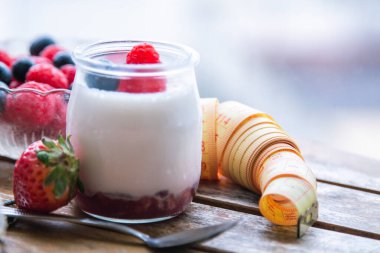 ahududulu yoğurt ve ahşap arka planda bant, diyet ve yiyecek konseptiyle yaban mersini.