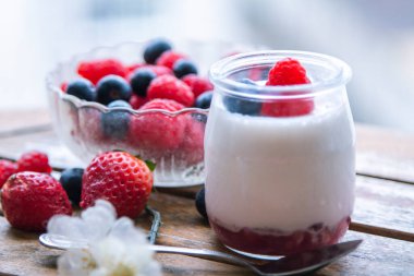 ahududulu yoğurt ve ahşap arka planda yaban mersini.