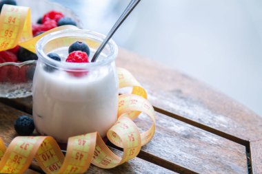 ahududulu yoğurt ve ahşap arka planda bant, diyet ve yiyecek konseptiyle yaban mersini.