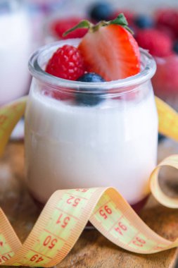 ahududulu yoğurt ve ahşap arka planda bant, diyet ve yiyecek konseptiyle yaban mersini.