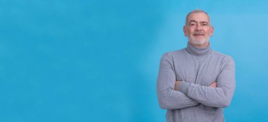 Yakışıklı, orta yaşlı, mutlu yüzlü, kendine güvenen, gülümseyen bir adam.