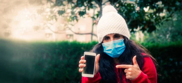 Menina Com Máscara Descartável Apontando Para Telefone Móvel — Fotografia de Stock