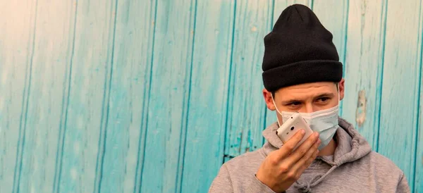 man with disposable surgical mask talking on the smartphone