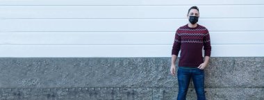 Yüzünde tıbbi maske olan genç bir adam kendini virüslerden ve enfeksiyonlardan koruyor. 