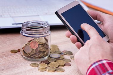 Adam cep telefonu ve para kavanozu kullanıyor, ekonomi ve tasarruf kavramı