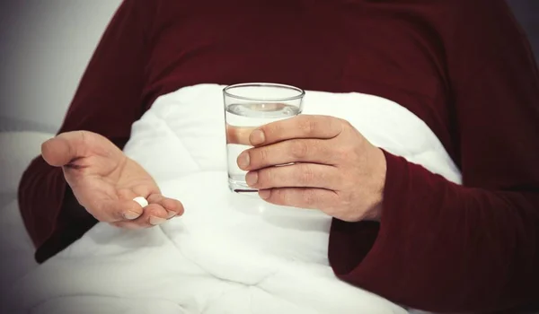 Άνθρωπος Στο Κρεβάτι Ένα Ποτήρι Νερό Και Χάπια — Φωτογραφία Αρχείου