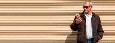 Şehirde cep telefonu kullanan güneş gözlüklü bir adam.