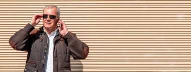 Yetişkin bir adam sokakta cep telefonuyla konuşuyor.