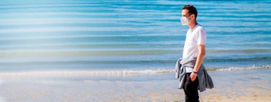 man with medical mask in protection of the coronavirus in the new normal walking on the beach