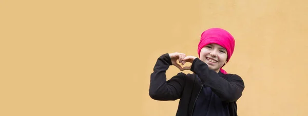 머리쓰개를 손으로 심장의 상징을 만드는 미소짓는 소녀의 — 스톡 사진