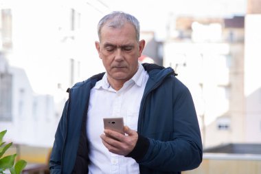 Sokakta cep telefonu kullanan çekici bir yetişkin adam.