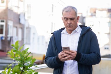 Sokakta cep telefonu kullanan çekici bir yetişkin adam.