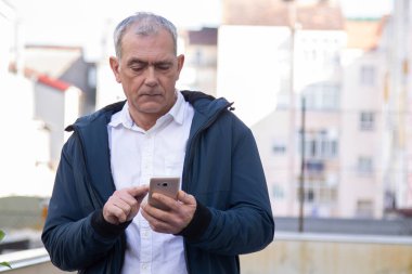 Çekici yetişkin adam caddede cep telefonunu kontrol ediyor.