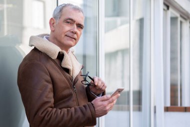 Gözlüklü yetişkin adam cep telefonu kullanıyor