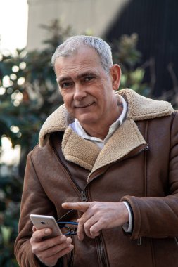 Akıllı telefon kullanan ceketli bir adam.