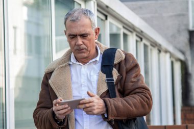  Yetişkin adam dizüstü bilgisayar taşıyor ve şehirde cep telefonu kullanıyor.