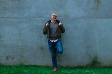 Duvarda gülümseyen yetişkin bir adam.