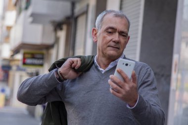 Sokakta cep telefonu kullanan çekici bir yetişkin adam.