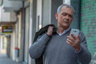 Sokakta cep telefonu kullanan çekici bir yetişkin adam.