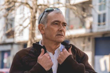 Şehirde yürürken ceketli olgun bir adamın portresi.