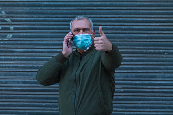 man with medical mask using mobile phone and doing ok with finger